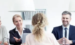 Zeigt eine Frau beim Vorstellungsgespräch von hinten. Ein Mann und eine Frau sind ihr zugewandt.